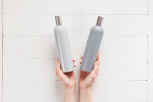 Can the wrong shampoo cause hair loss? A woman holding two shampoo bottles