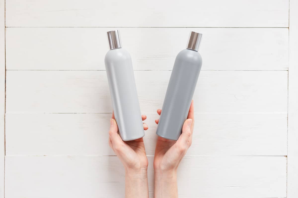 Can the wrong shampoo cause hair loss? A woman holding two shampoo bottles