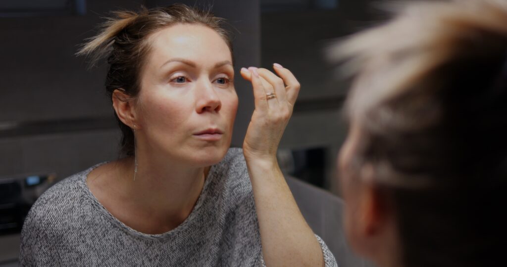 Woman lean and look mirror and check her sparse eyebrows.