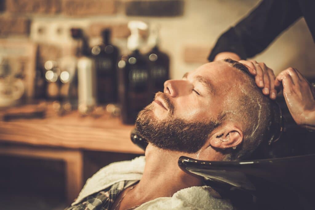 Hairstylist washing client's hair in barber shop after a hair transplant