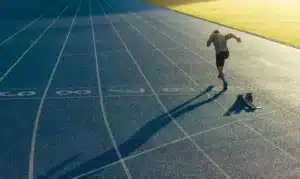 Un athlète en position de départ sur une piste de sprint, prêt à s'élancer.